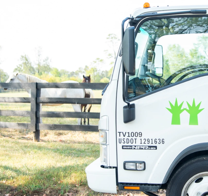 A Landscape Workshop truck with a fence and horses in the background.