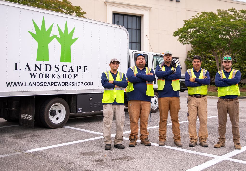 Five men in front of a Landscape Workshop truck with a business in the background.